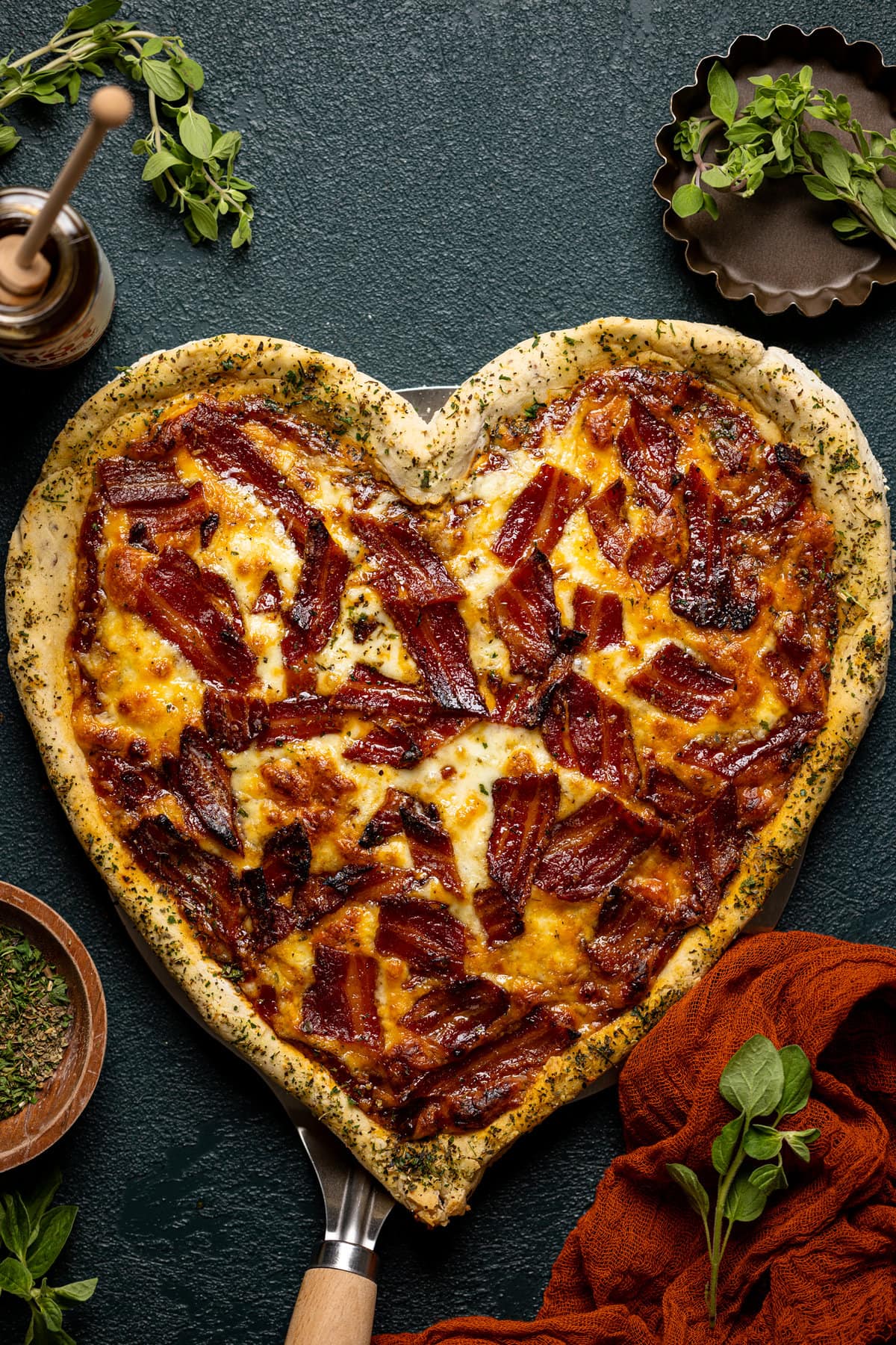 Overhead shot of heart-shaped Gluten-Free Hot Honey Bacon Pizza