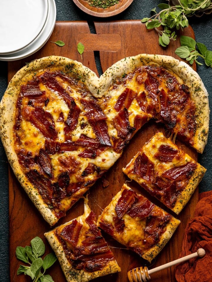 Heart-shaped Gluten-Free Hot Honey Bacon Pizza being cut into pieces