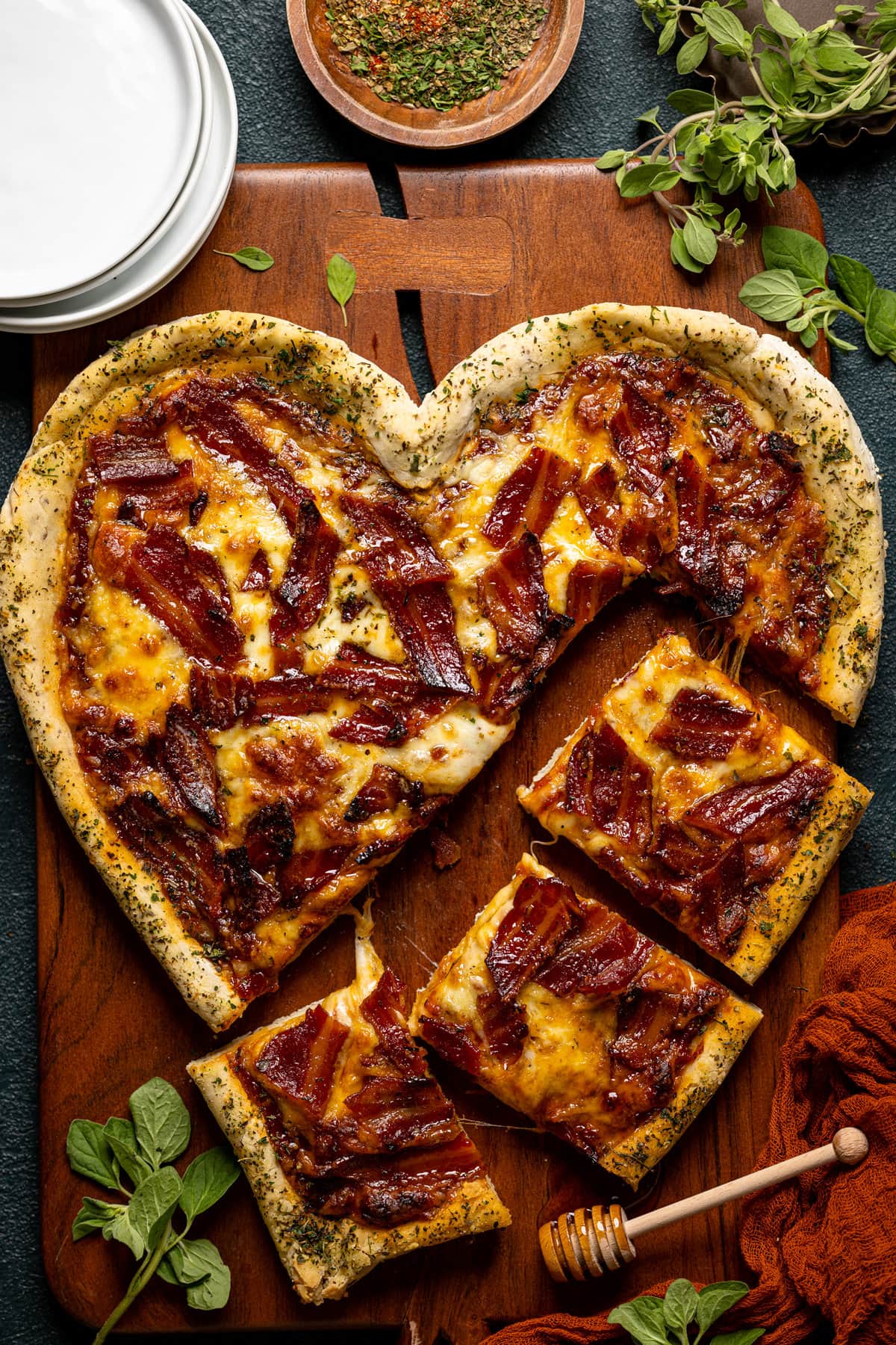 Heart-shaped Gluten-Free Hot Honey Bacon Pizza being cut into pieces