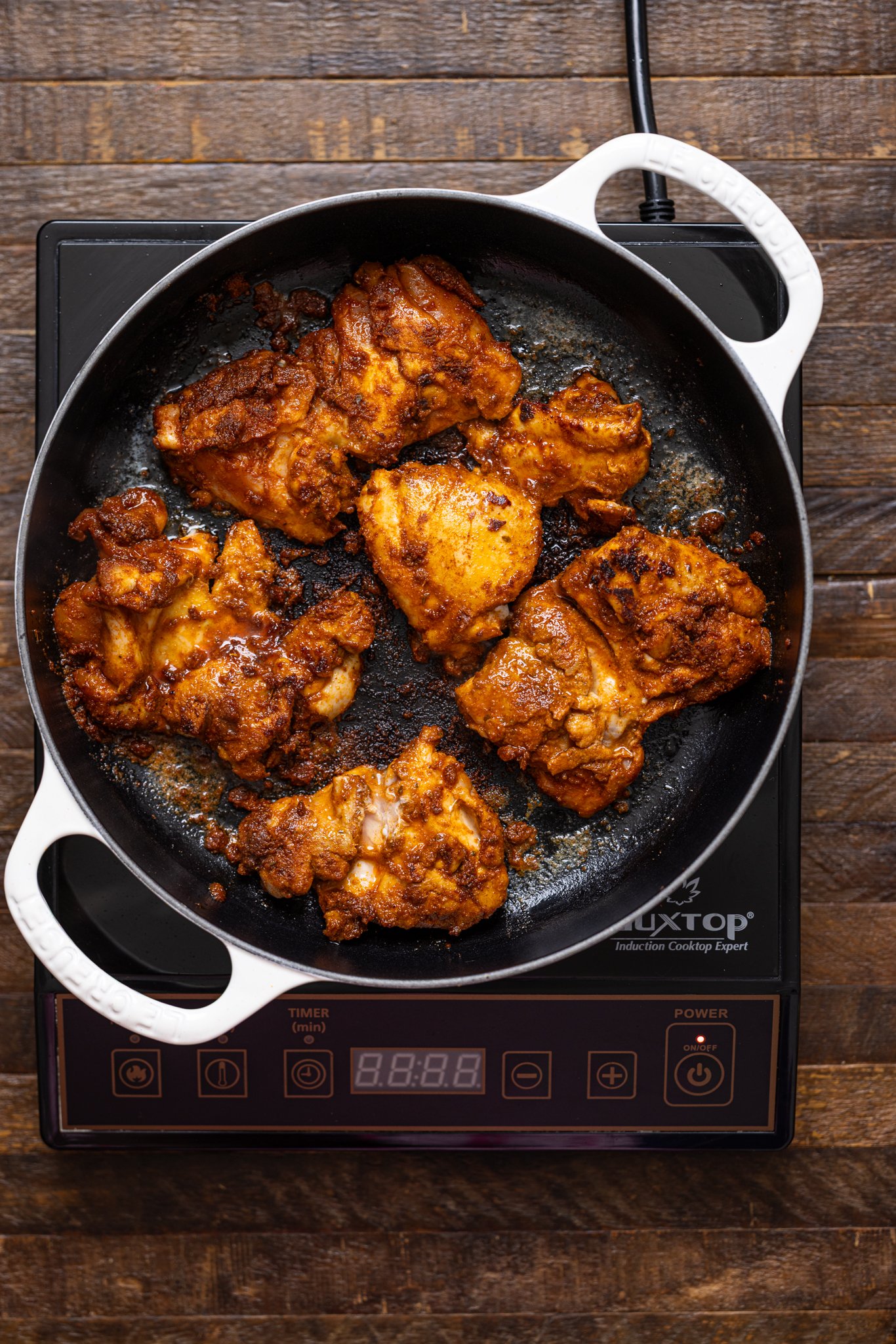 Seared chicken in a skillet over a stovetop.