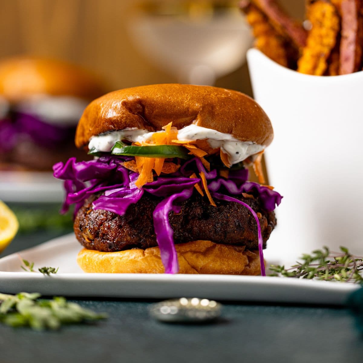 Loaded salmon burger on a white plate with french fries.