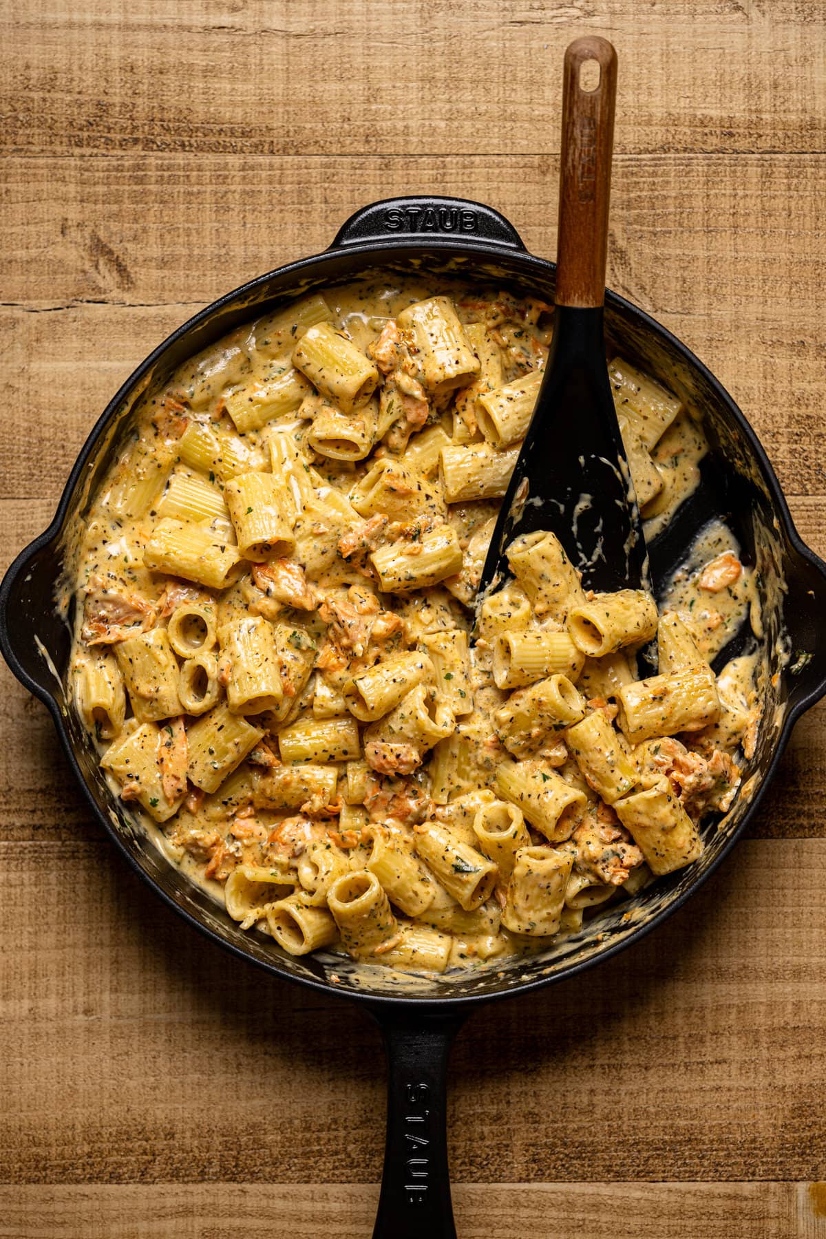 Spoon stirring Creamy Salmon Alfredo Pasta in a pan