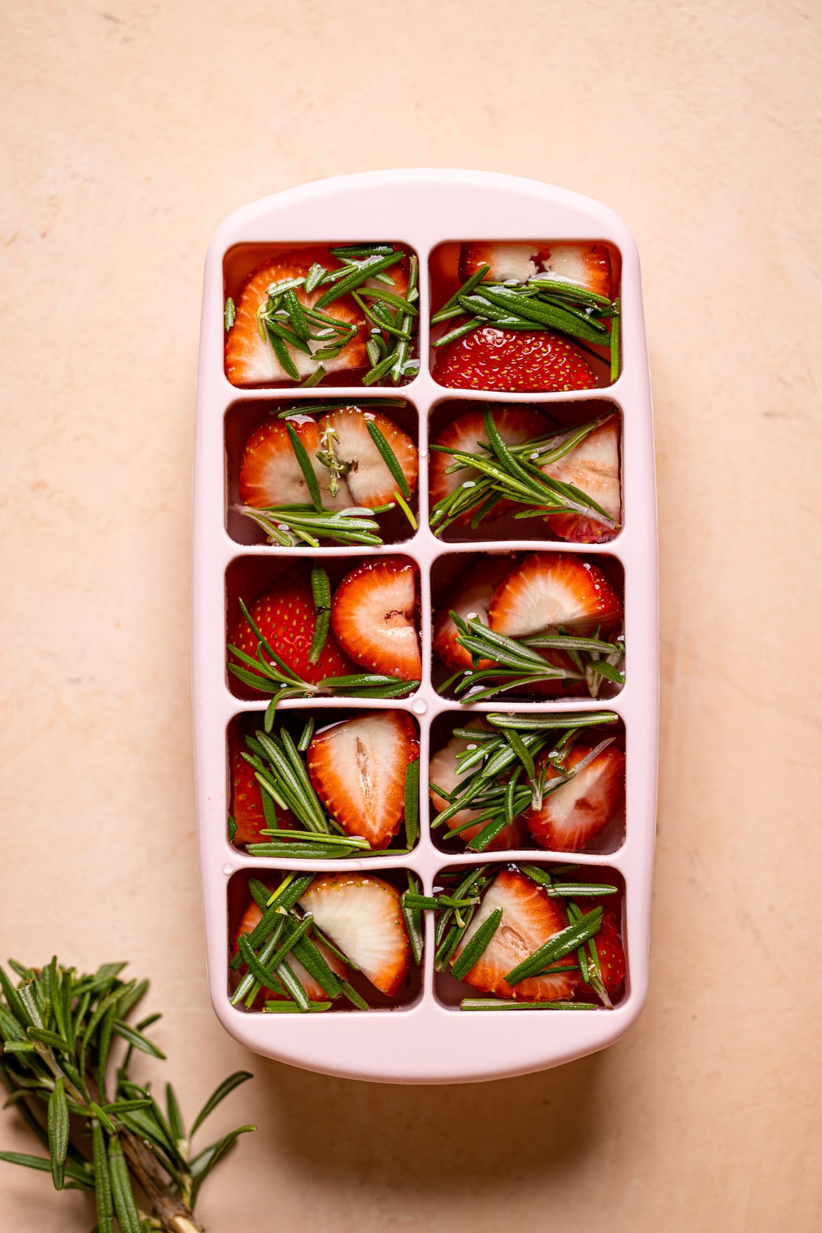 Tray of unfrozen strawberry-rosemary ice cubes