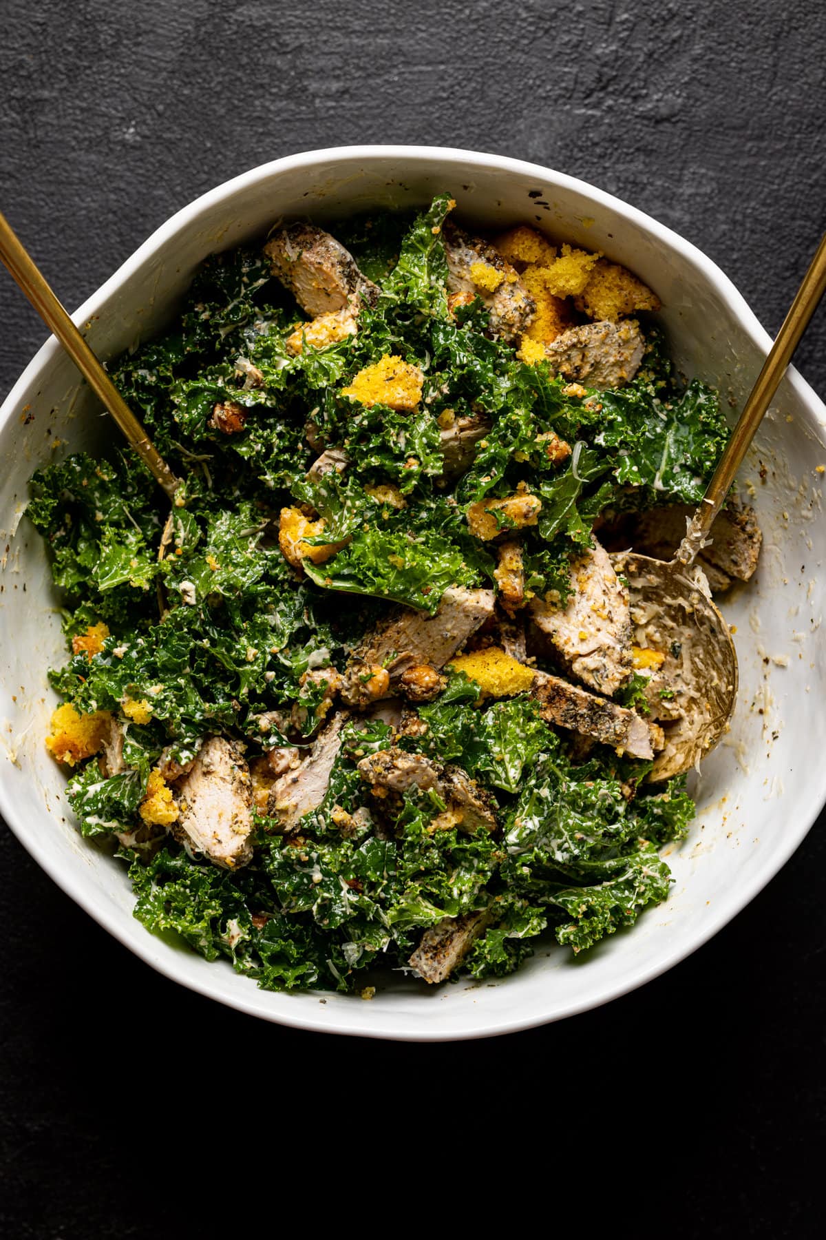 Chicken Caesar Salad being tossed in a bowl