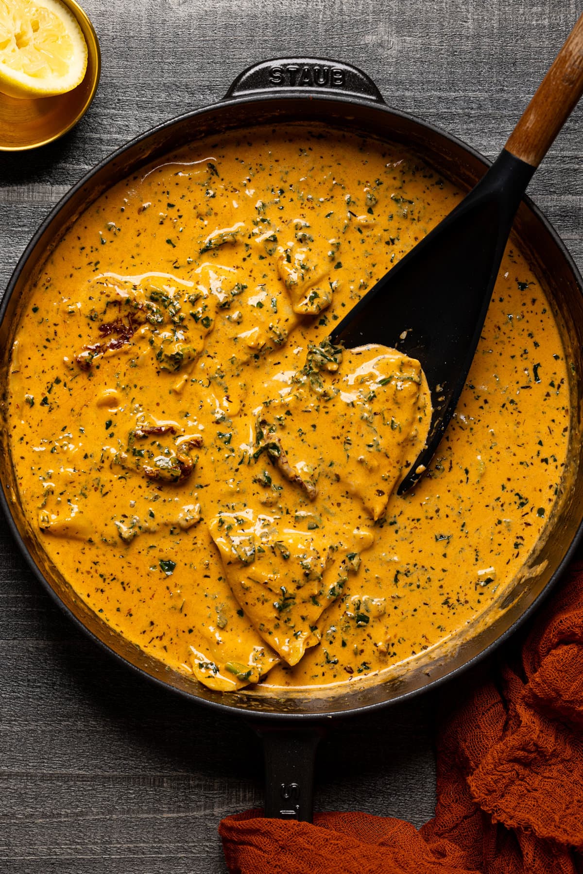 Spoon stirring sauce and ravioli in a pan