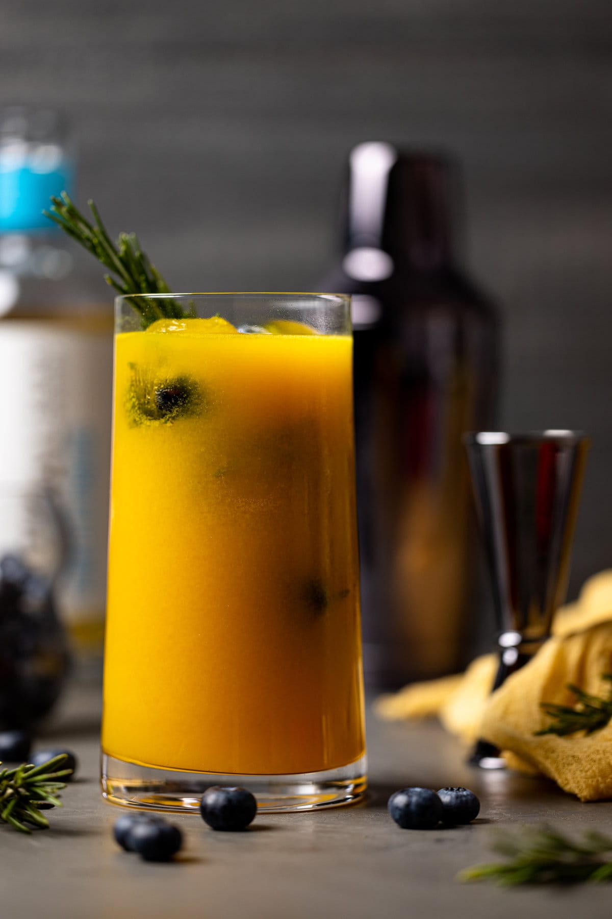 Glass of Mango Lemonade Kombucha Mocktail with a tumbler in the background