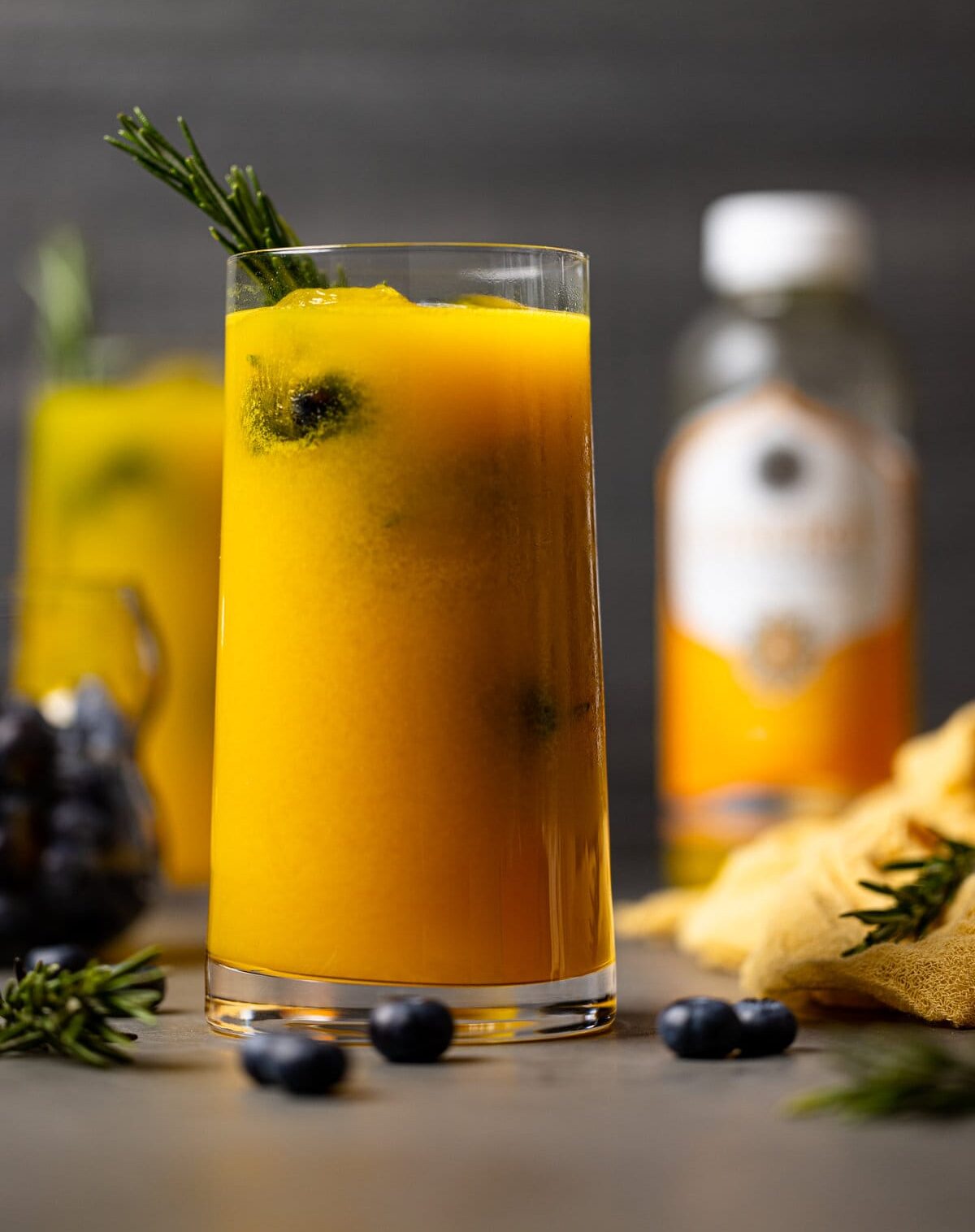 Glass of Mango Lemonade Kombucha Mocktail with a sprig of rosemary