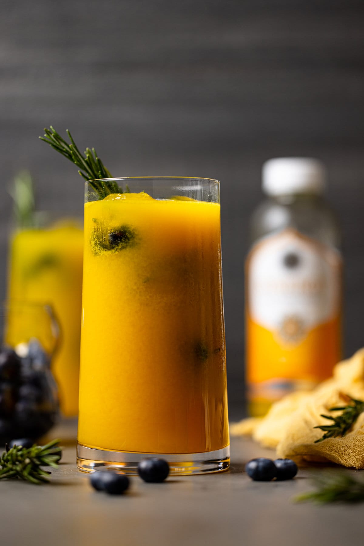 Glass of Mango Lemonade Kombucha Mocktail with a sprig of rosemary