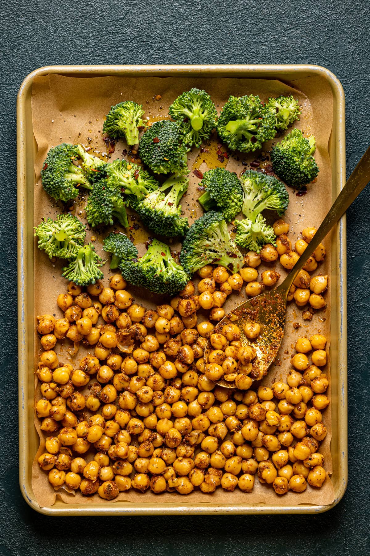 Broccoli and chickpeas on a baking tray with a spoon