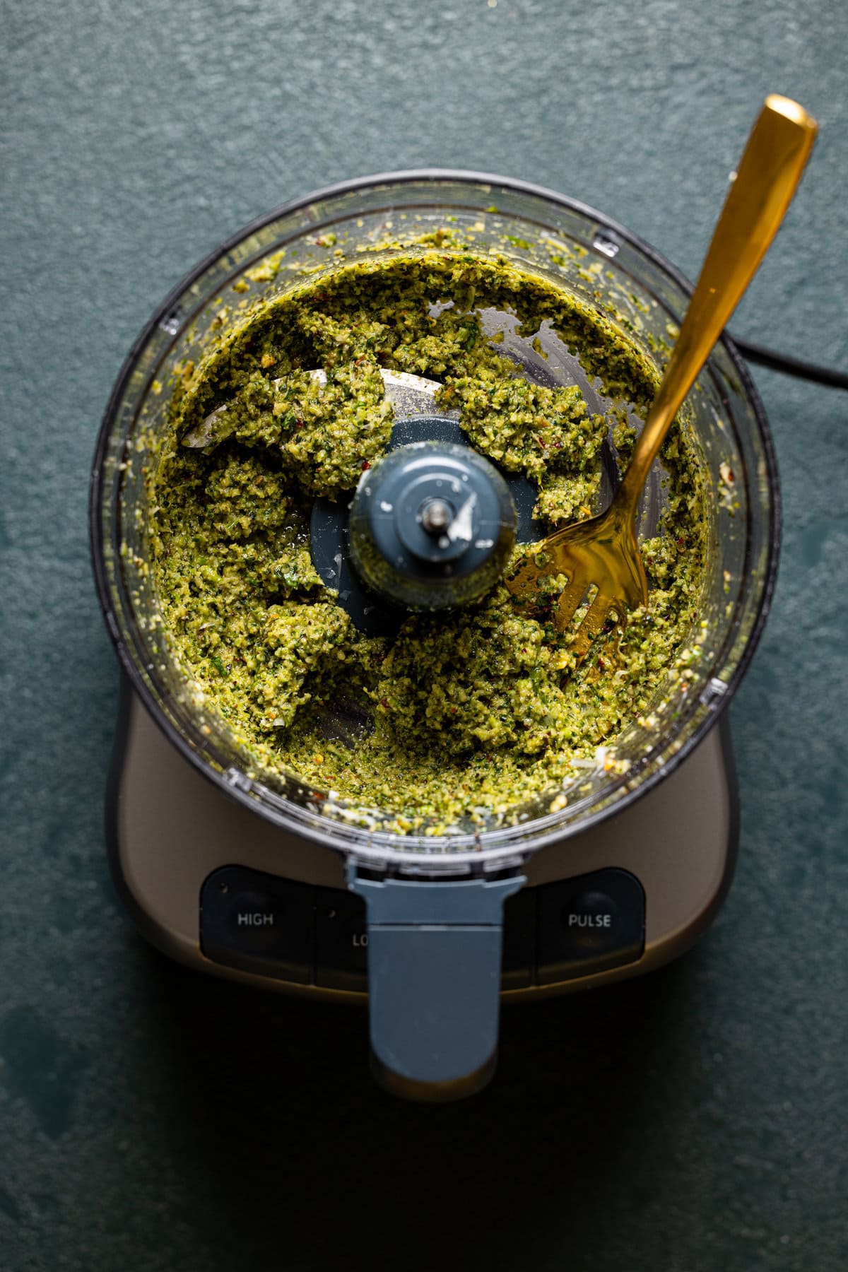 Broccoli pesto in a food processor with a fork