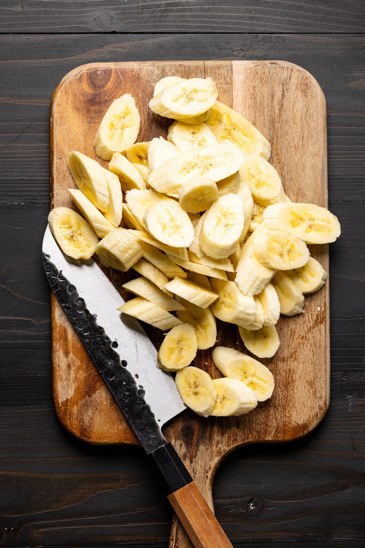 Sliced bananas on a cutting board with a knife