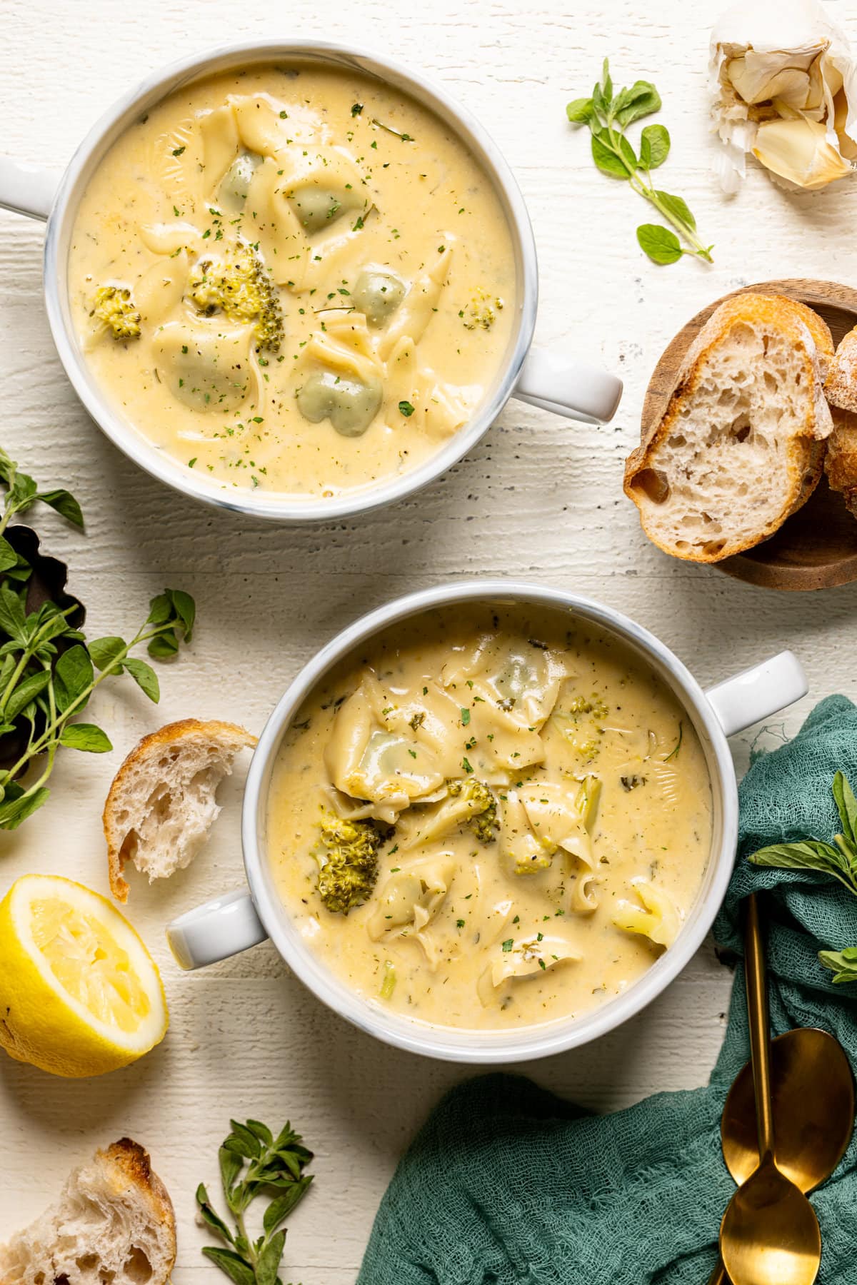 Overhead shot of two bowls of Creamy Lemon Broccoli Tortellini Soup with handles