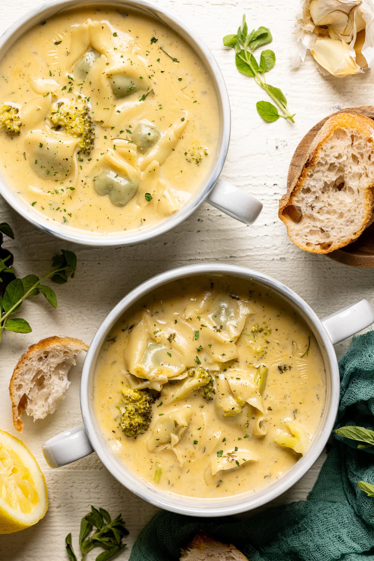 Overhead shot of two bowls of Creamy Lemon Broccoli Tortellini Soup with handles