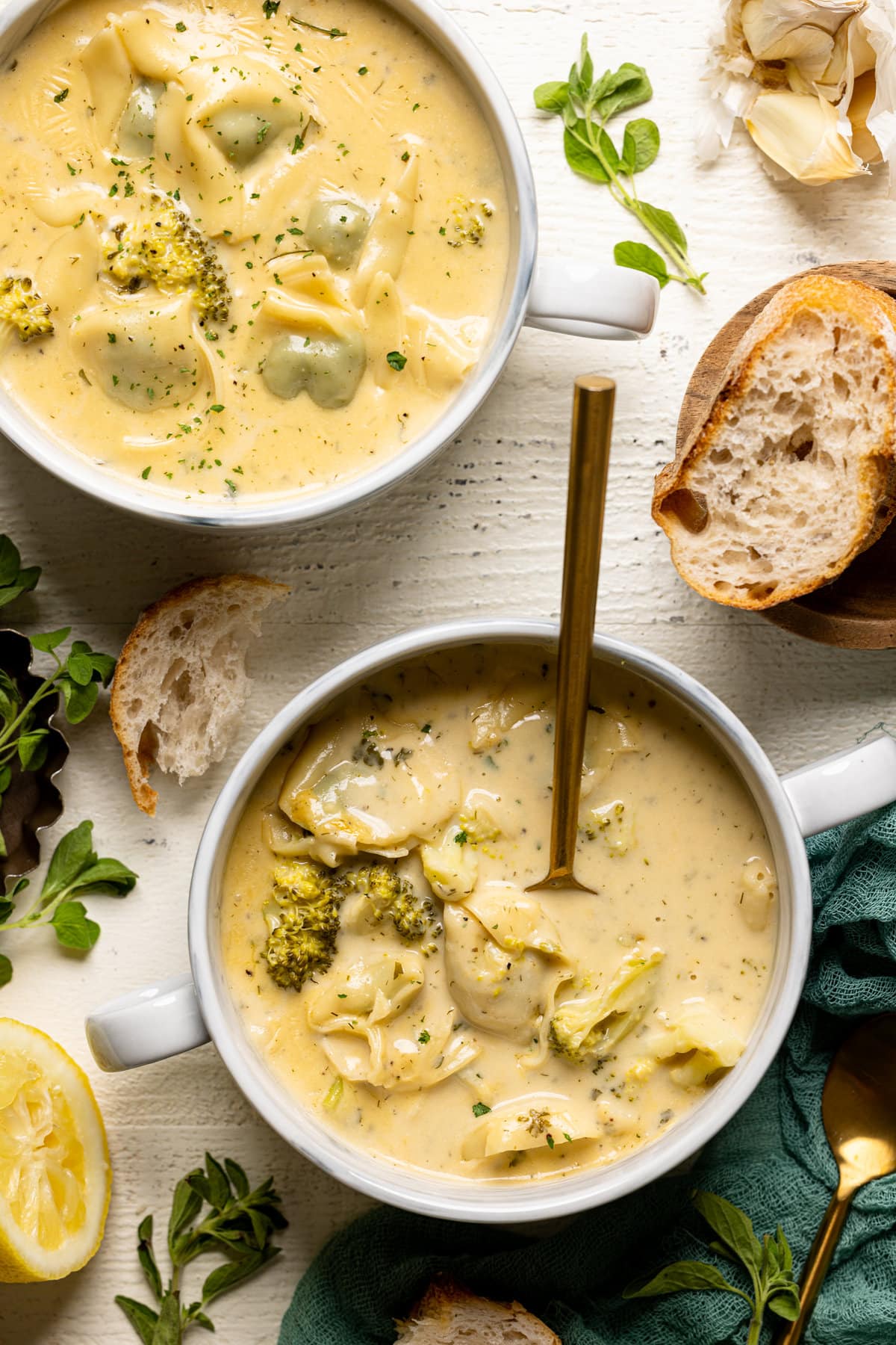 Overhead shot of two bowls of Creamy Lemon Broccoli Tortellini Soup with bread