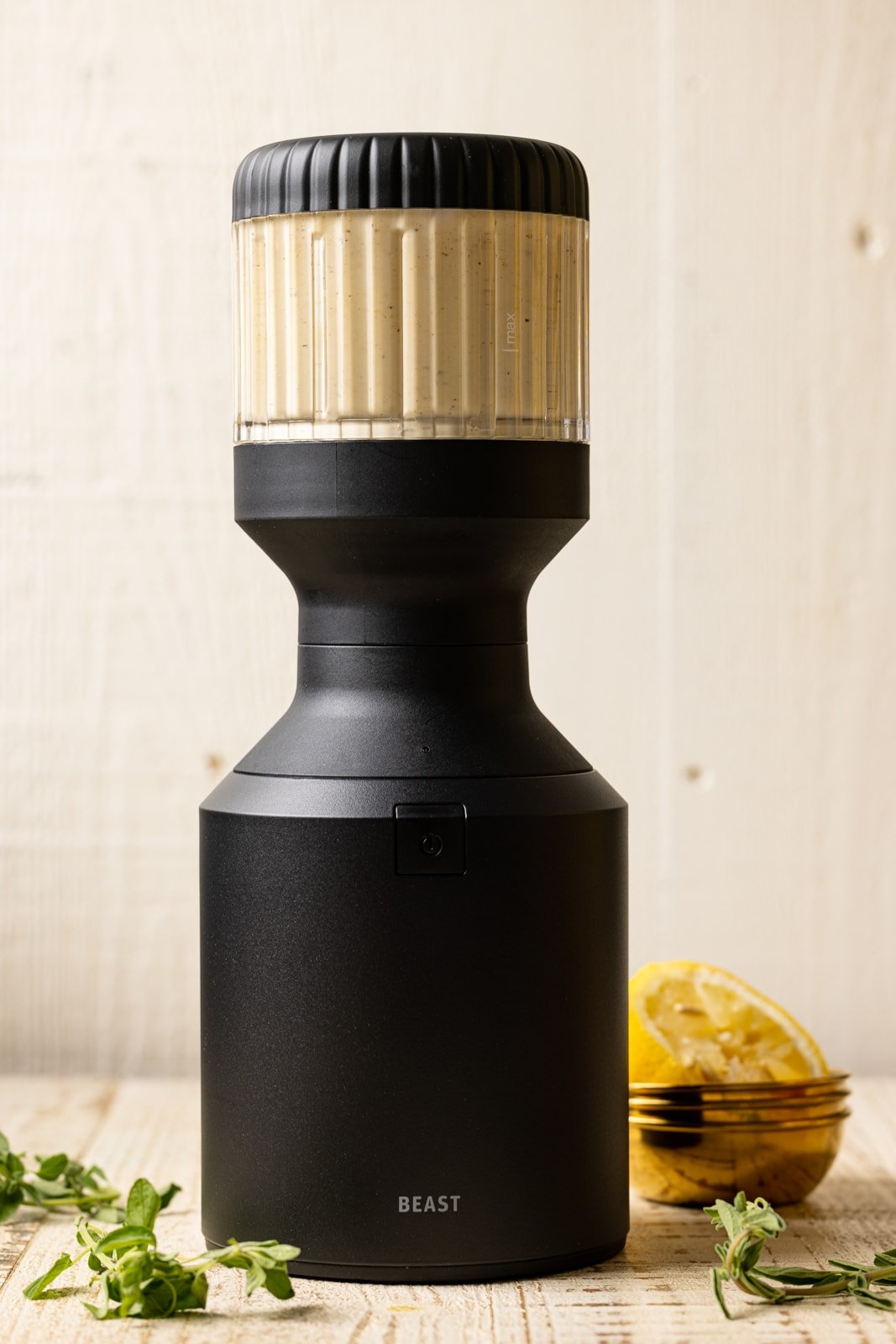 Honey mustard in a black blender being shown on a white wood table.