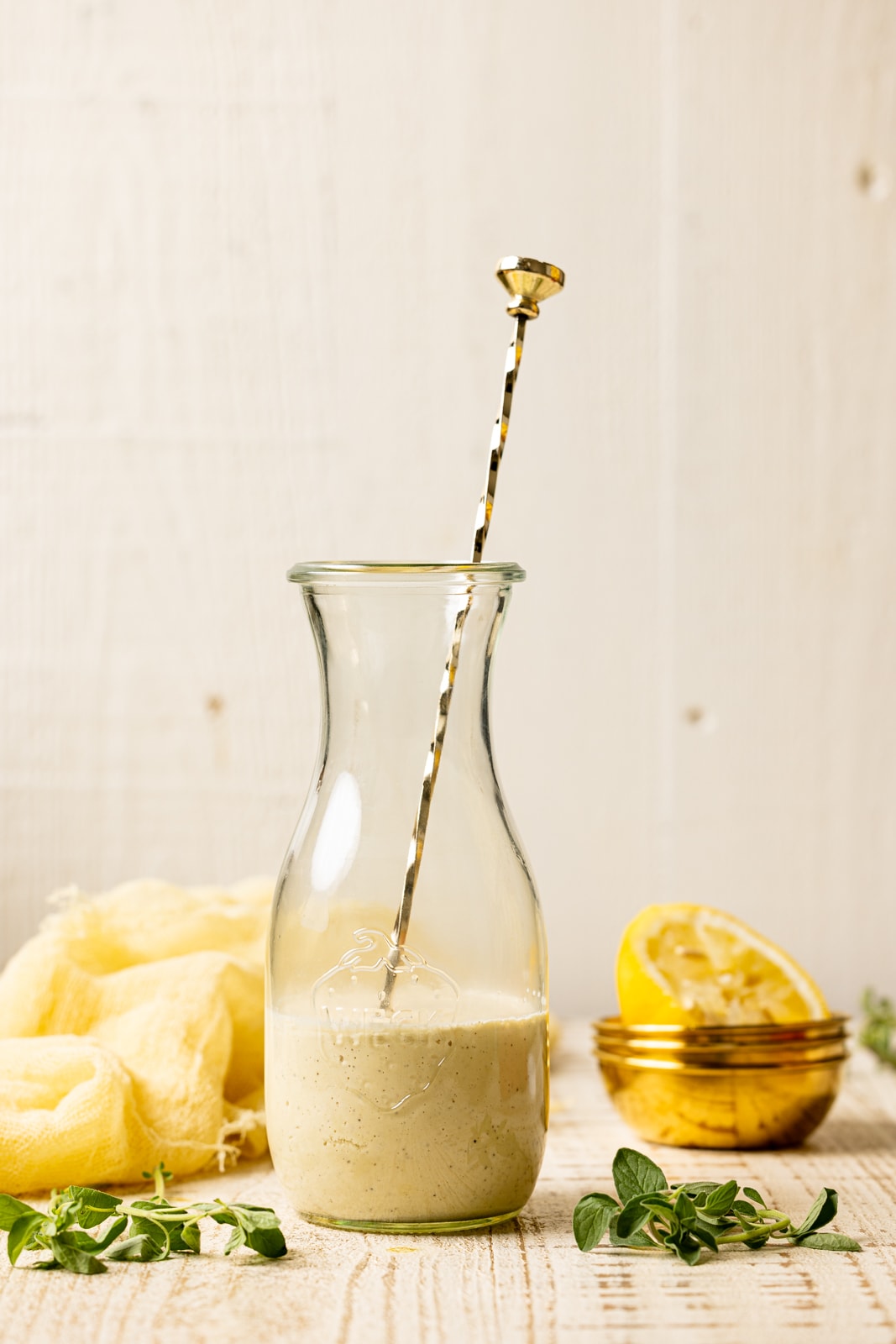 Honey mustard in a jar with a gold long spoon inside of the jar on a white wood table.