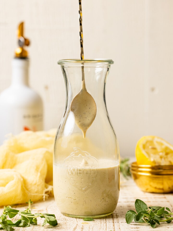 Honey mustard dressing dripping from a spoon into a jar.