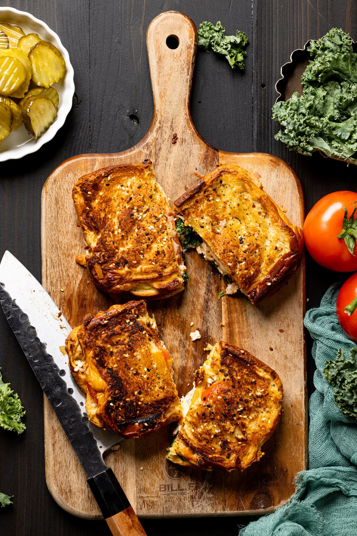 Two Everything Chicken Tomato Grilled Cheese Sandwiches on a cutting board with a knife