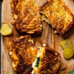 Two Everything Chicken Tomato Grilled Cheese Sandwiches on a cutting board