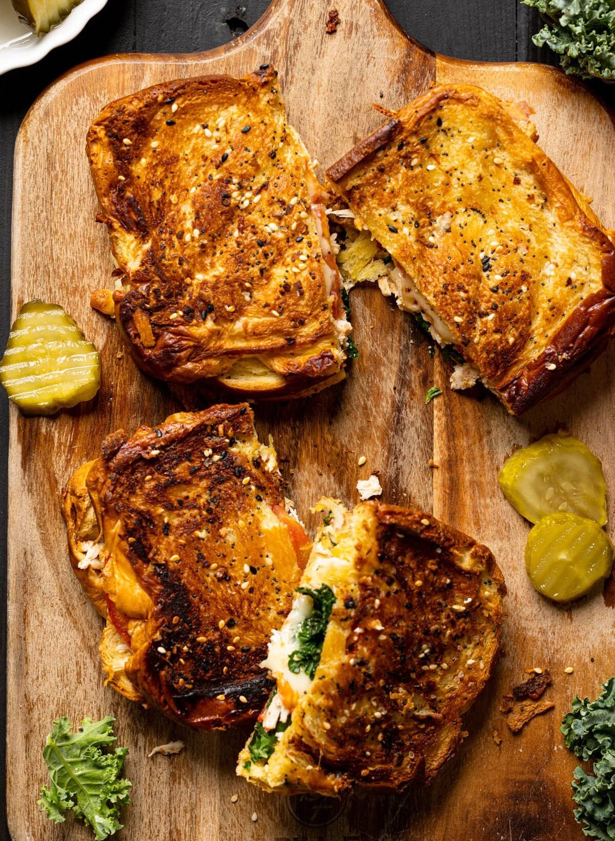 Two Everything Chicken Tomato Grilled Cheese Sandwiches on a cutting board