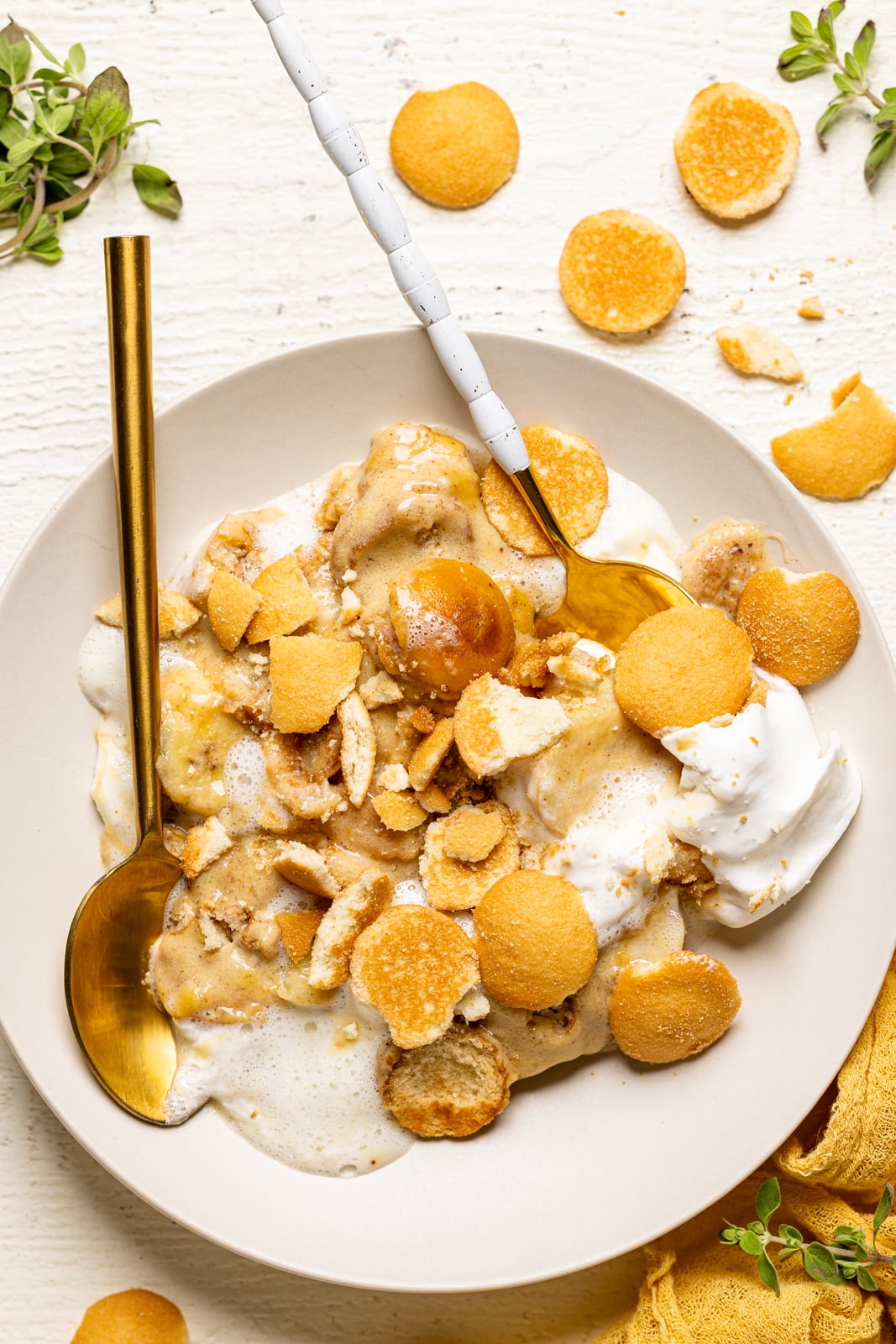 Baked banana pudding in a plate with two spoons on a white table.