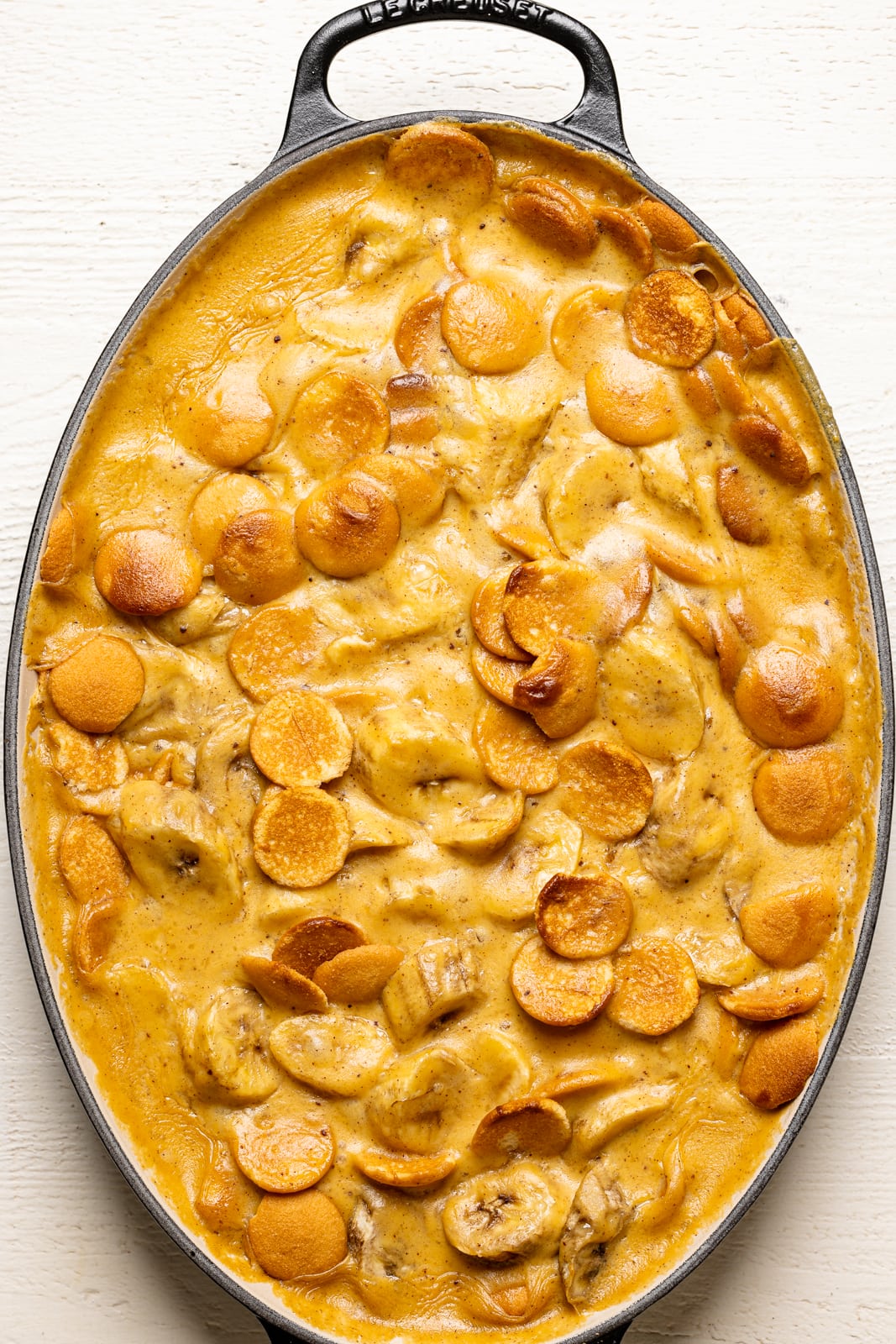 Baked banana pudding out of the oven in a baking dish on a white table. 