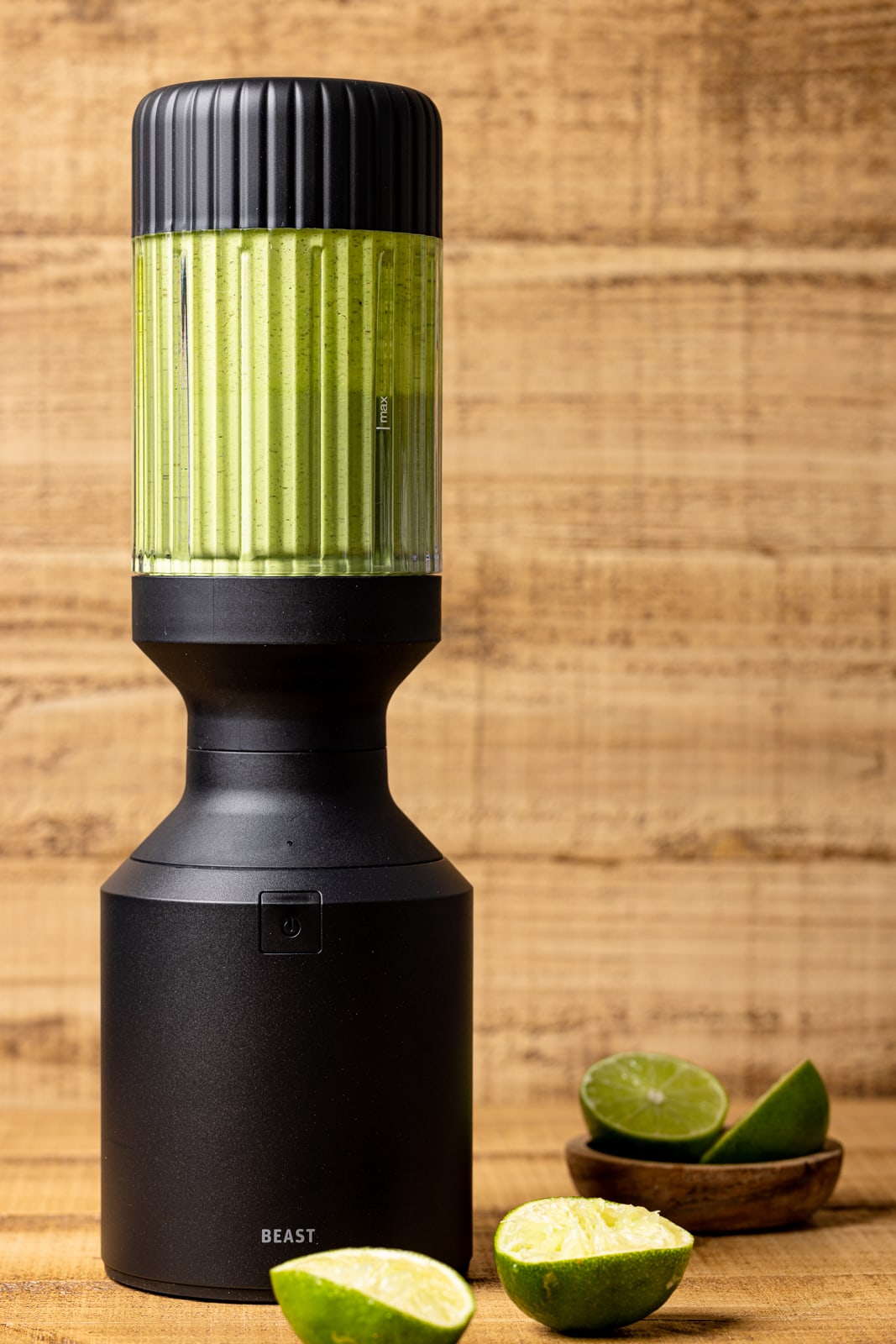 Green goddess dressing in a black blender on a brown wood table. 