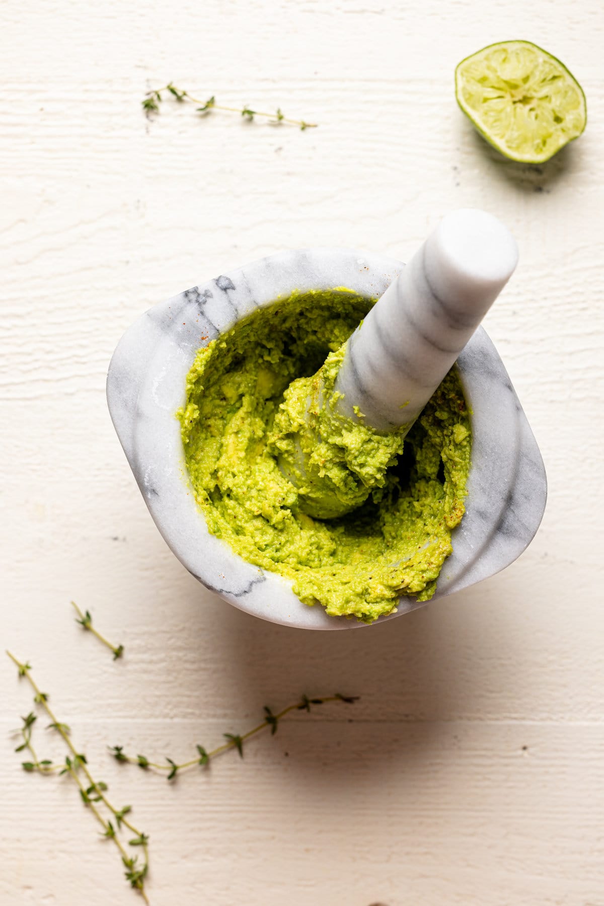 Mashed avocado with a mortar and pestle on a table.