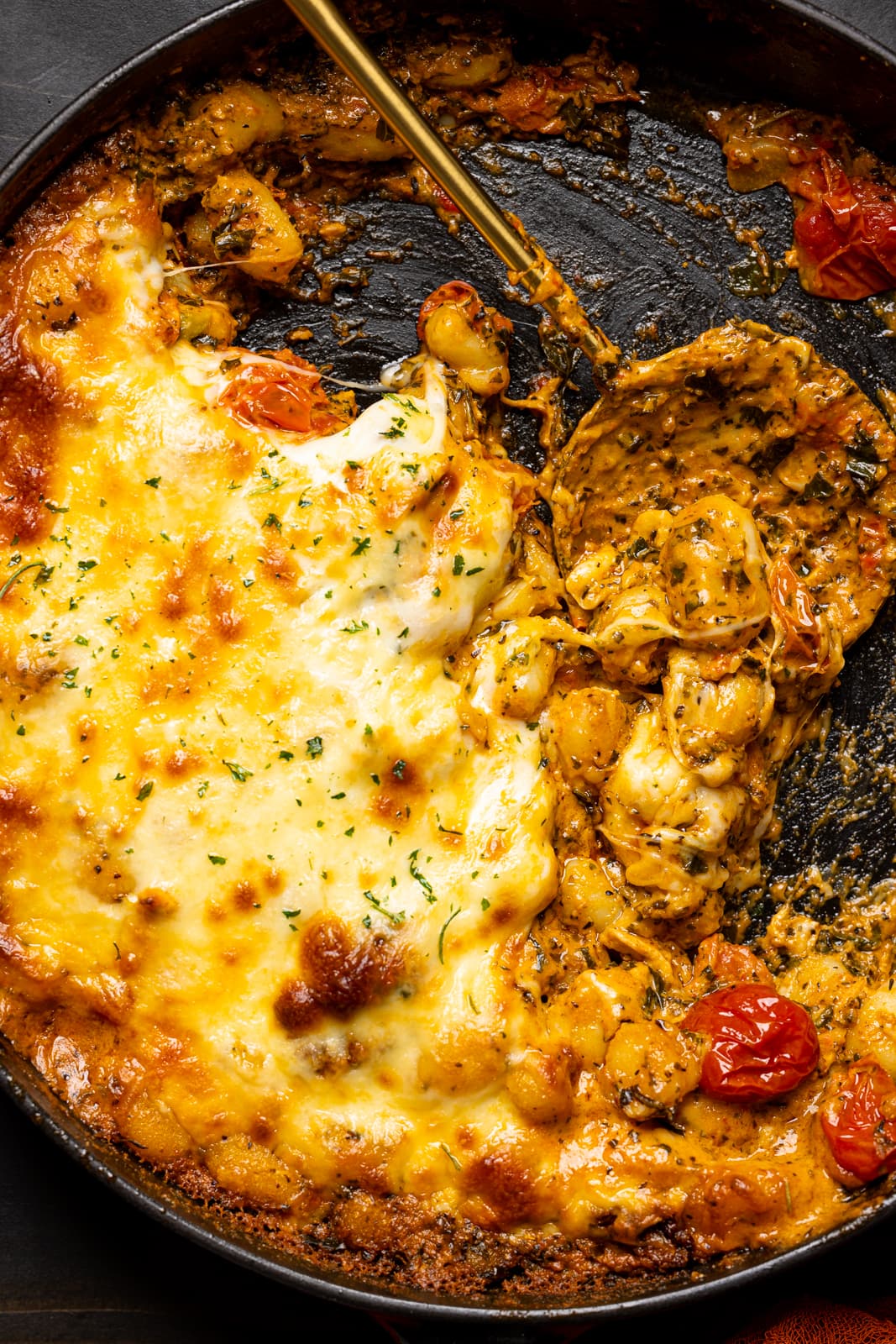 Chicken and gnocchi scooped out of skillet with a spoon.