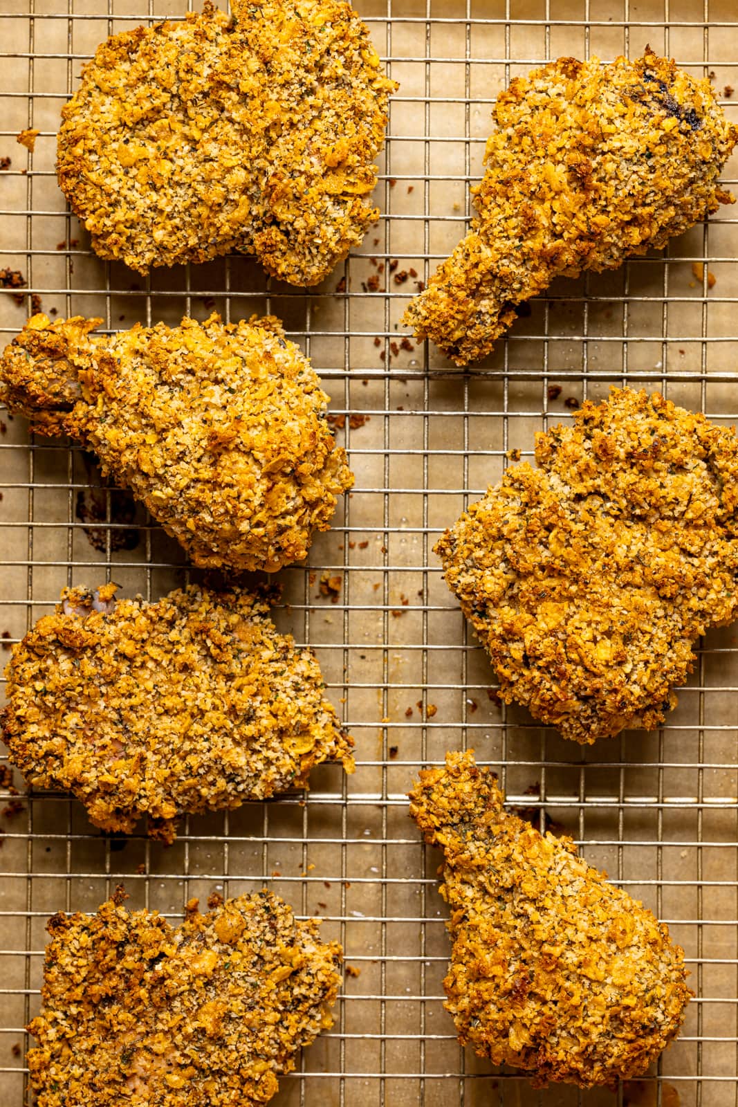 Coated chicken lined on a baking sheet with a wire rack.