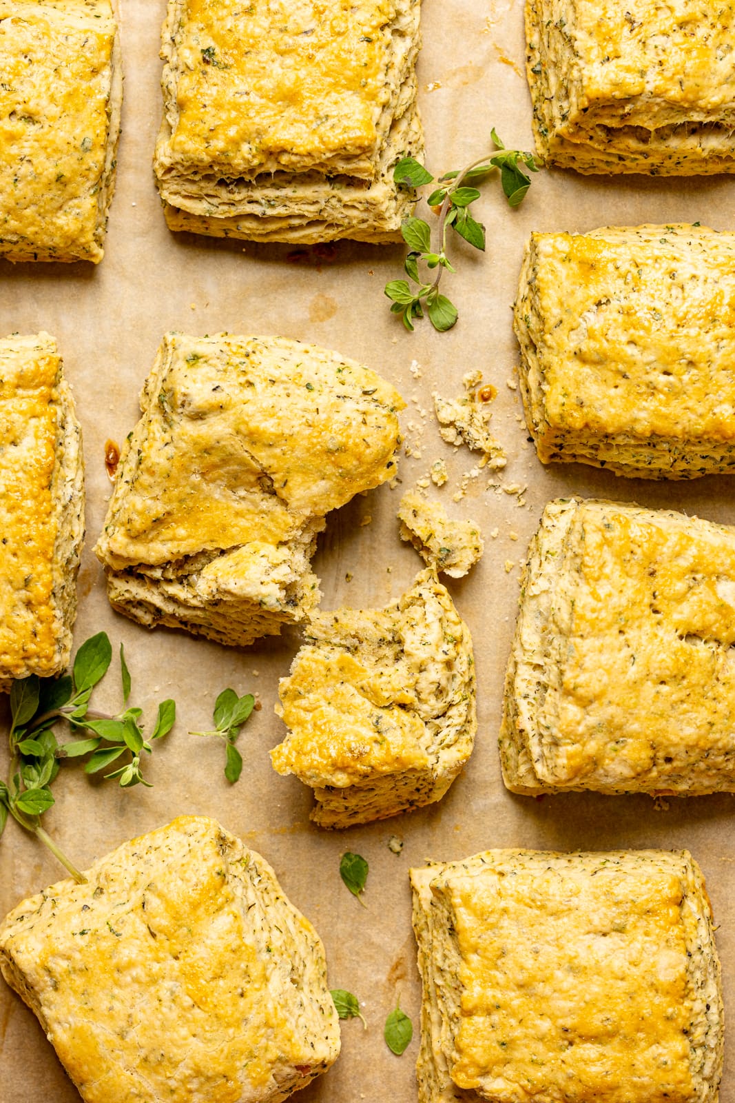 Biscuits on a baking sheet with parchment paper lined side by side with a broken biscuit.