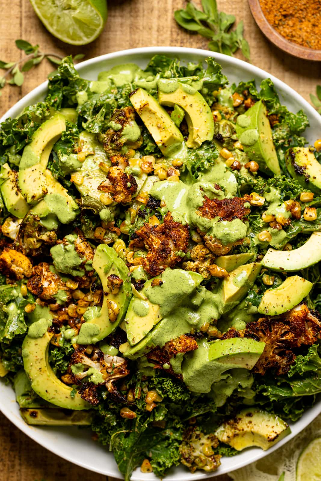 Up close shot of salad in a white round plate on a brown wood table.