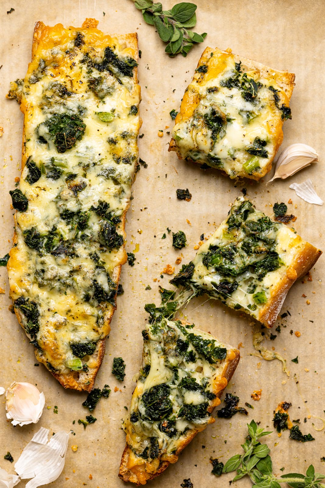 Baked french bread sliced on a baking sheet on a parchment paper with garlic and herbs.