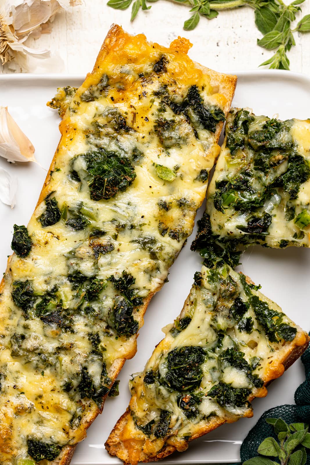 Baked French bread on a white plate with garlic and herbs. 