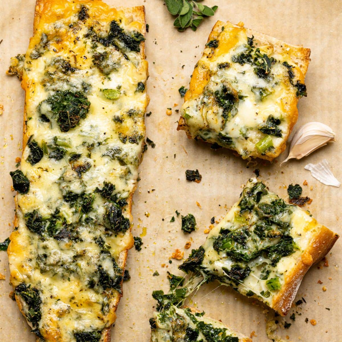 Baked french bread sliced on a baking sheet on a parchment paper with garlic and herbs.