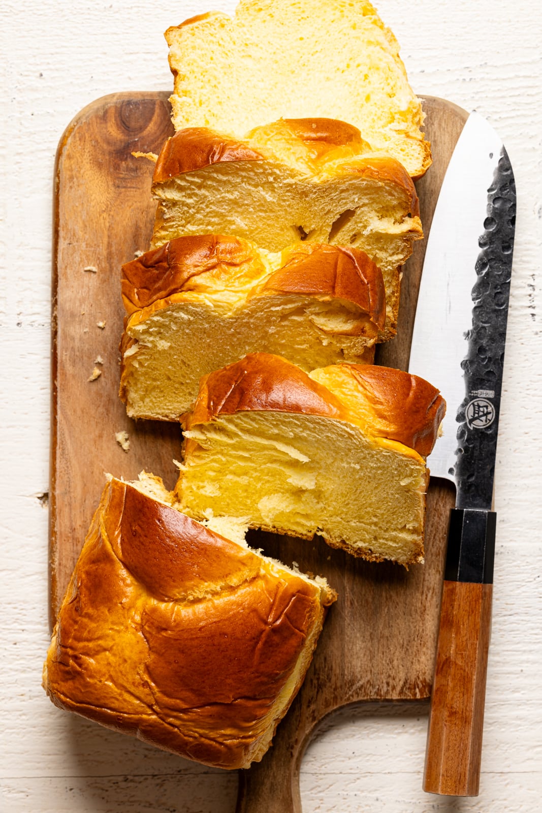 Loaf of brioche bread sliced on a cutting board with knife.