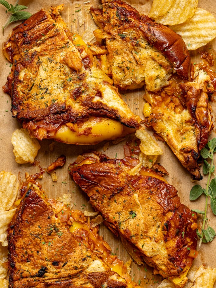 Up close shot of baked grilled cheeses on a baking sheet with parchment paper and chips.