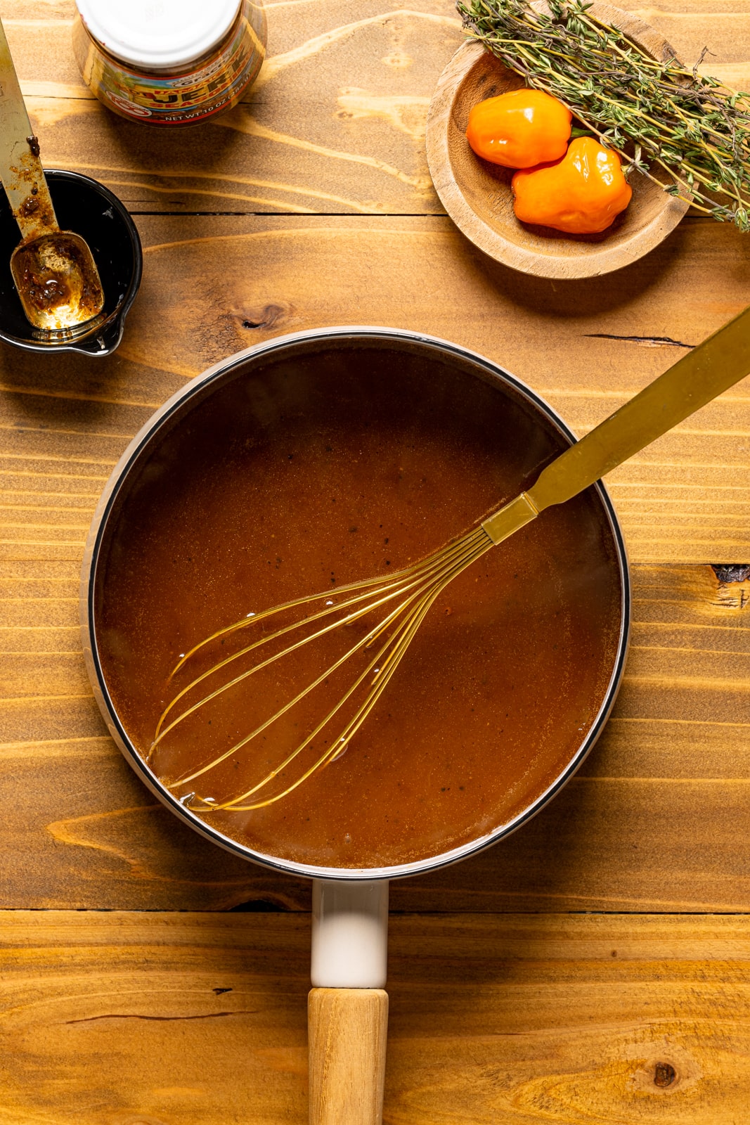 Barbeque jerk sauce in a pot with a whisk on a brown wood table.