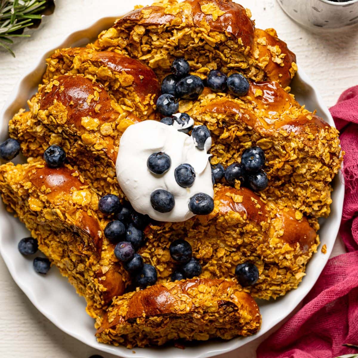 Up close shot of baked french toast in a white baking dish with blueberries.