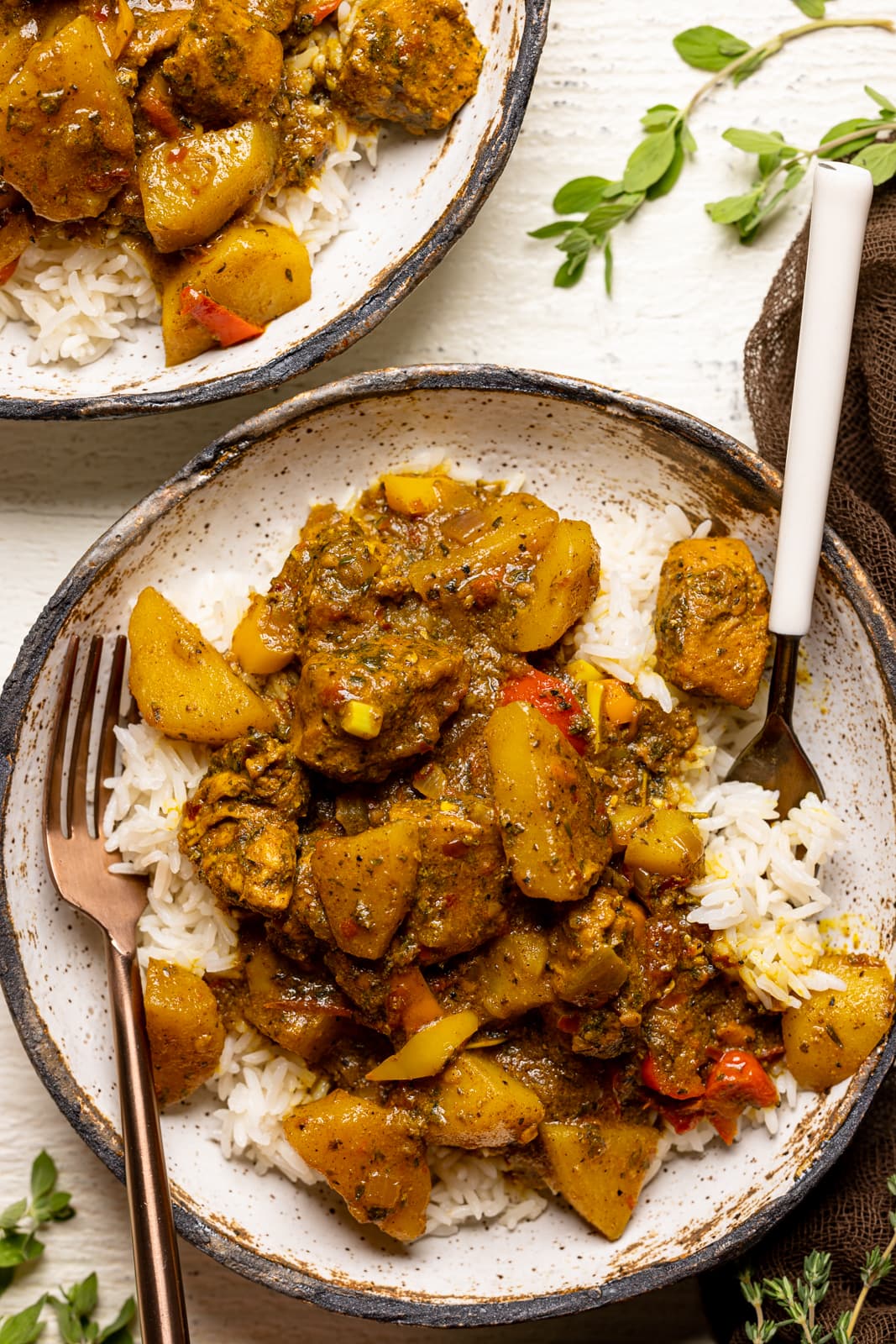 Up close shot of curry chicken dish with two forks on a white table.