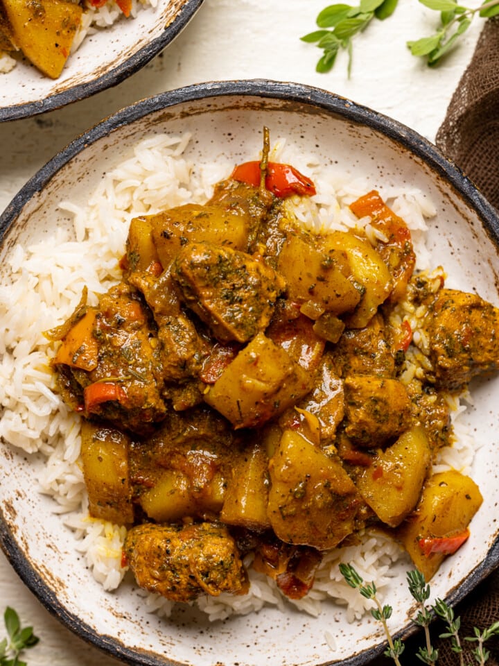 Up close shot of curry chicken in a bowl with herbs.