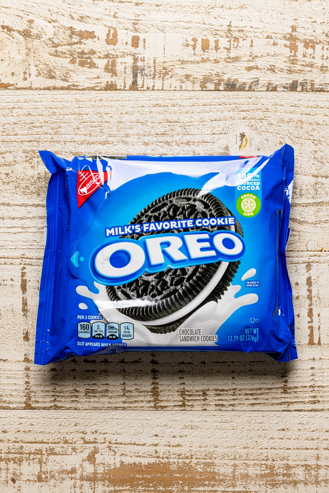 Pack of oreo cookies in a blue package on a white wood table.