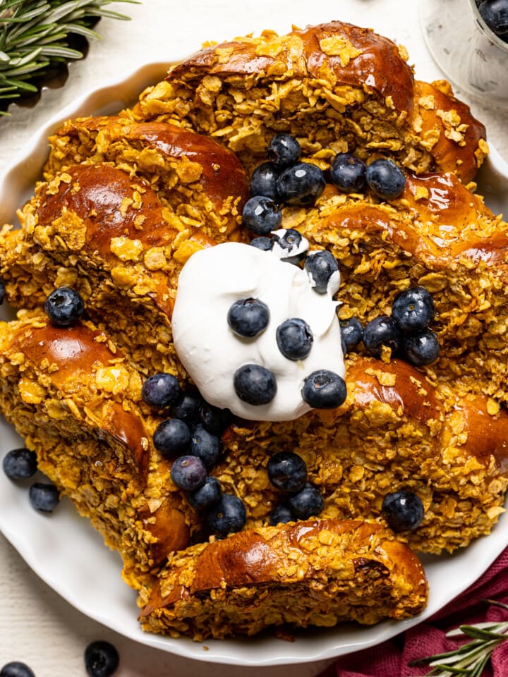 Up close shot of baked french toast in a white baking dish with blueberries.