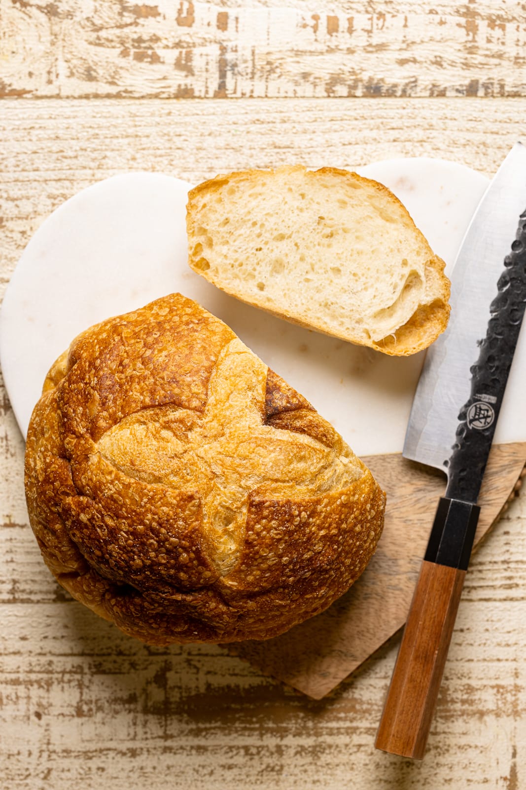 Rustic bread on a cutting board sliced with a knife. 