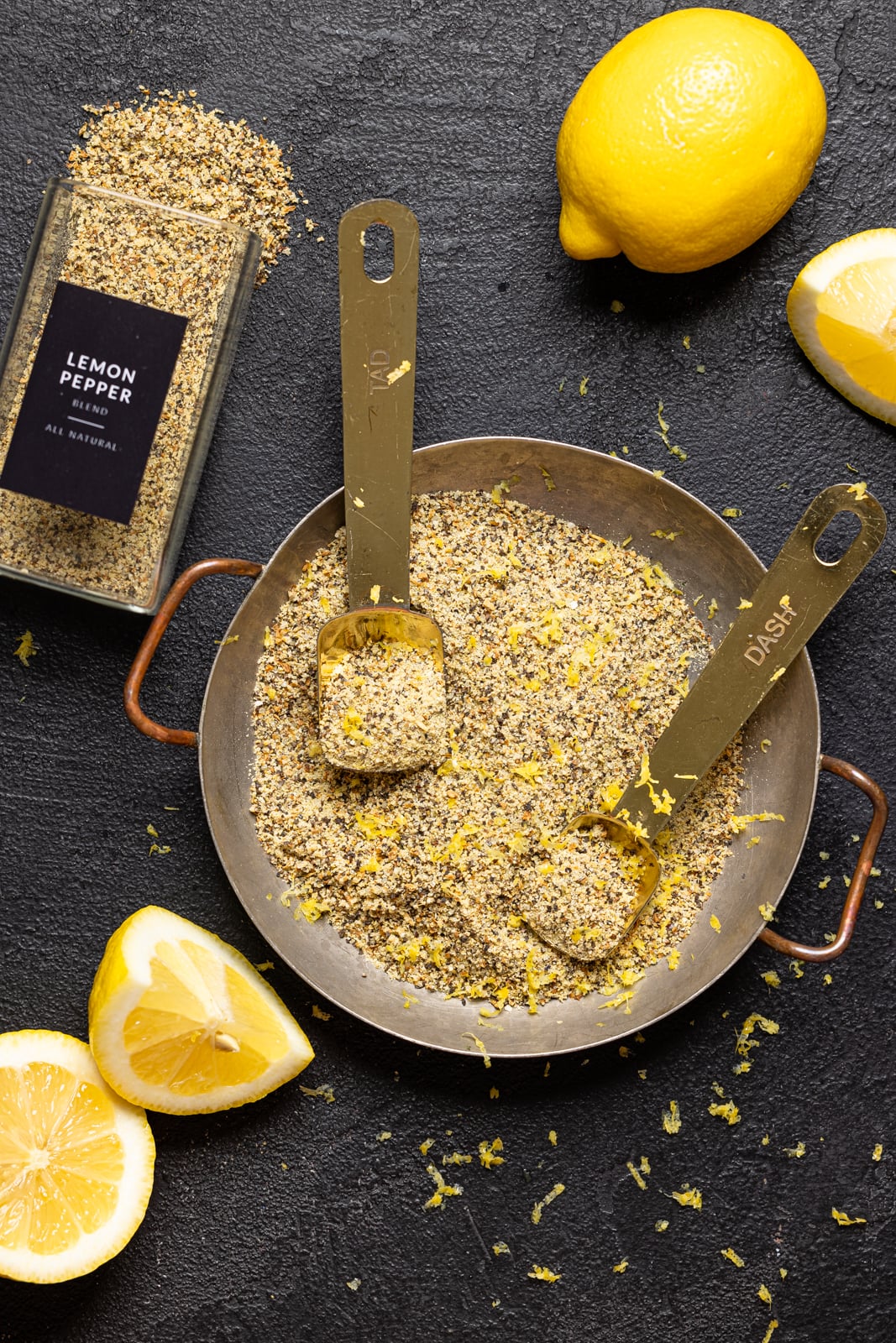 All ingredients on a black table with lemons and a seasoning jar.