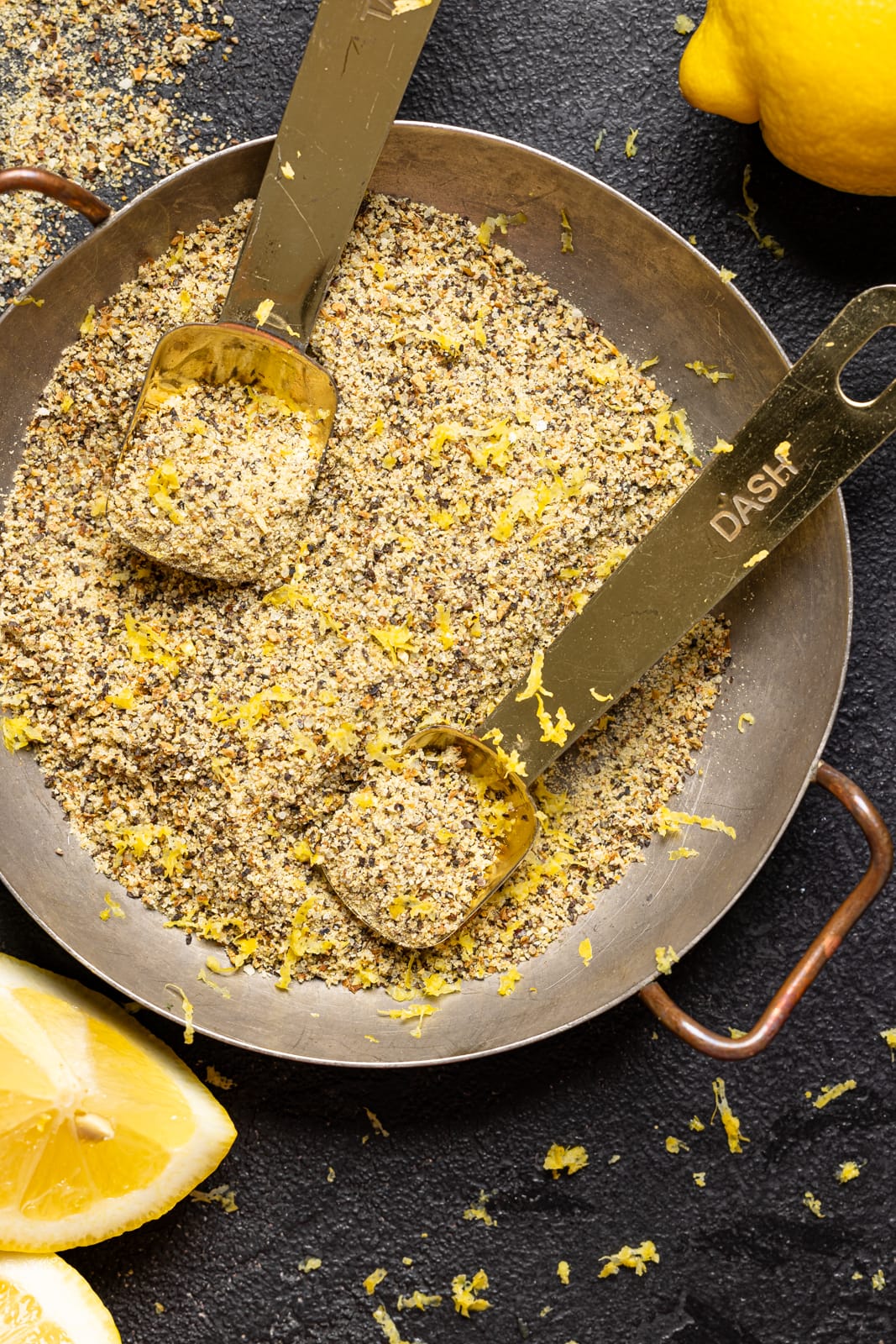 Up close shot of seasoning blend with lemons on a black table.