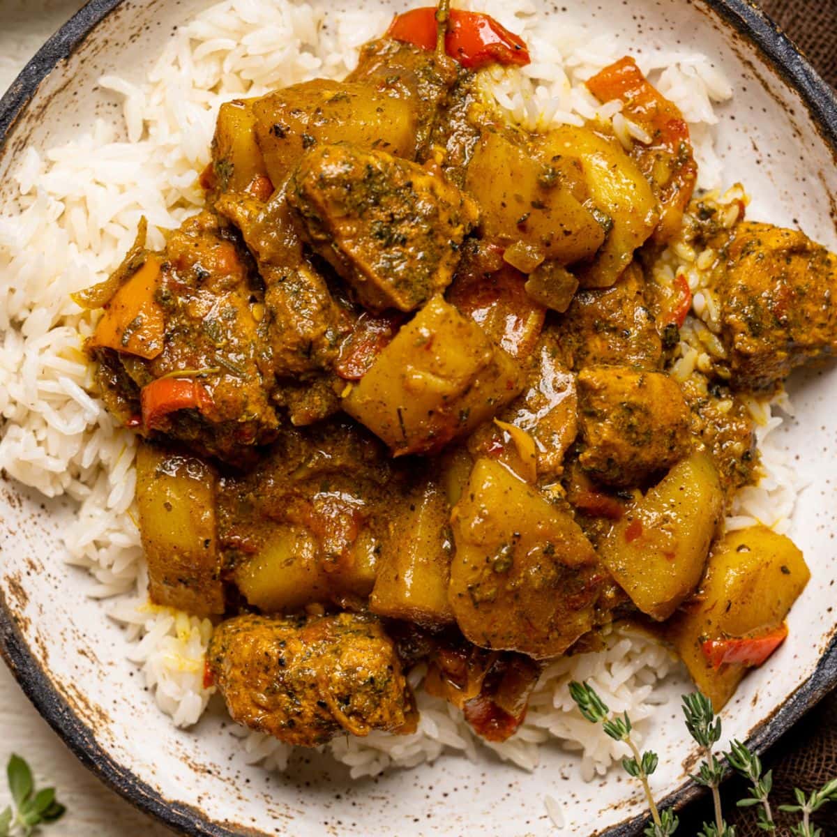 Up close shot of curry chicken in a bowl with herbs.