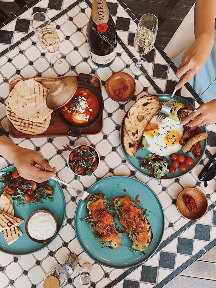 Black and white tiled table set with blue plates and several different foods.