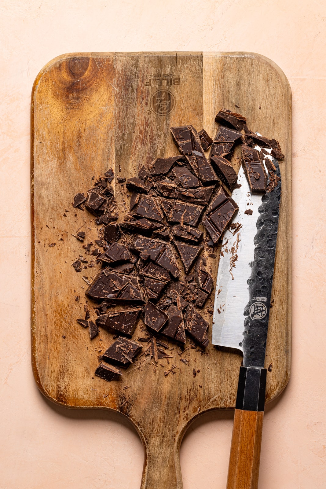 Chopped chocolate on a cutting board with a knife.