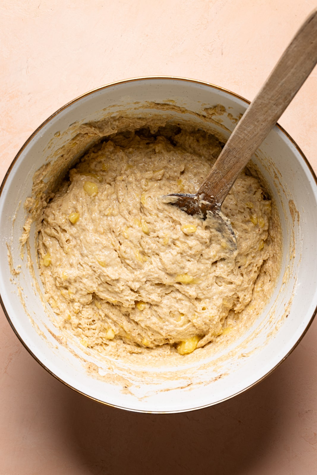 Vegan Banana Bread Recipe. The batter in a white bowl with a wooden spoon.